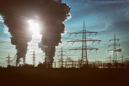 Silhouettes of electricity pylons and two power plants with pollution