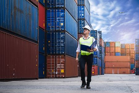 Foreman holding document, walking and checking the containers box from cargo ship for export and import