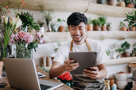 Mann mit Tablet im Blumengesch&auml;ft