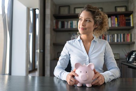 Junge Frau mit Sparschwein denkt nach