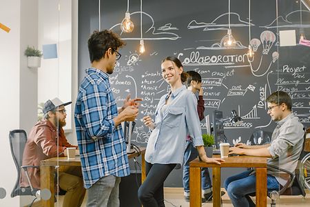 junge Leute beim Networken vor einer beschriebenen Tafel