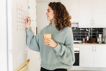 junge Frau tr&auml;gt etwas in Kalender ein