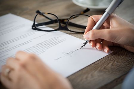 Hand h&auml;lt Stift und unterzeichnet einen Vertrag