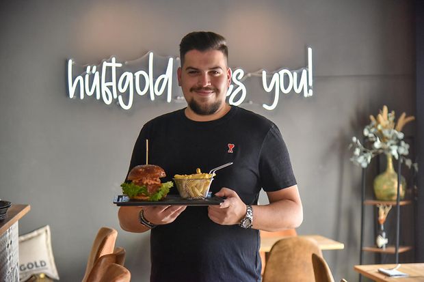 Dario Troncone, Inhaber des Restaurants H&uuml;ftgold in Schwetzingen, mit Burger und Pommes in der Hand.