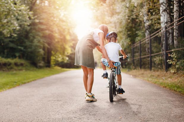 Mutter mit Sohn, der Fahrrad fahren lernt