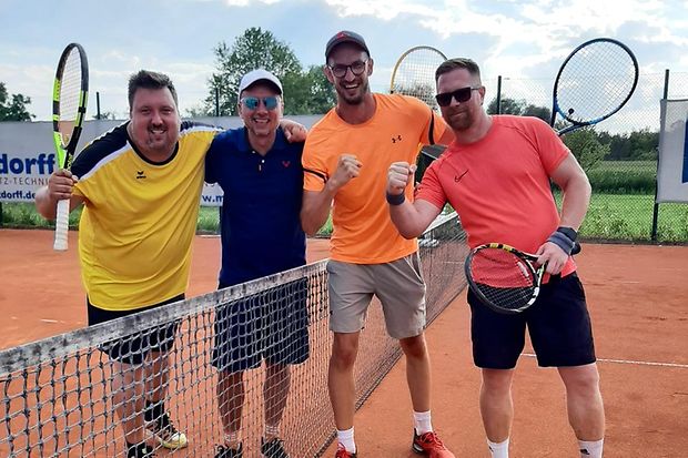 Kai Baumg&auml;rtner (2. von rechts) auf dem Tennisplatz mit Tennisschl&auml;ger und weiteren Spielern in Siegerpose