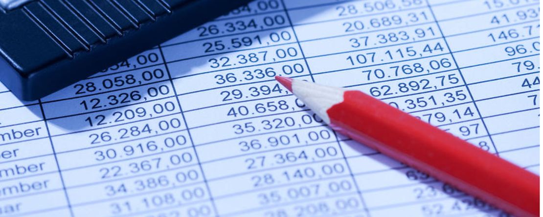 Taschenrechner und Rotstift liegen auf ausgedruckten Bilanzen