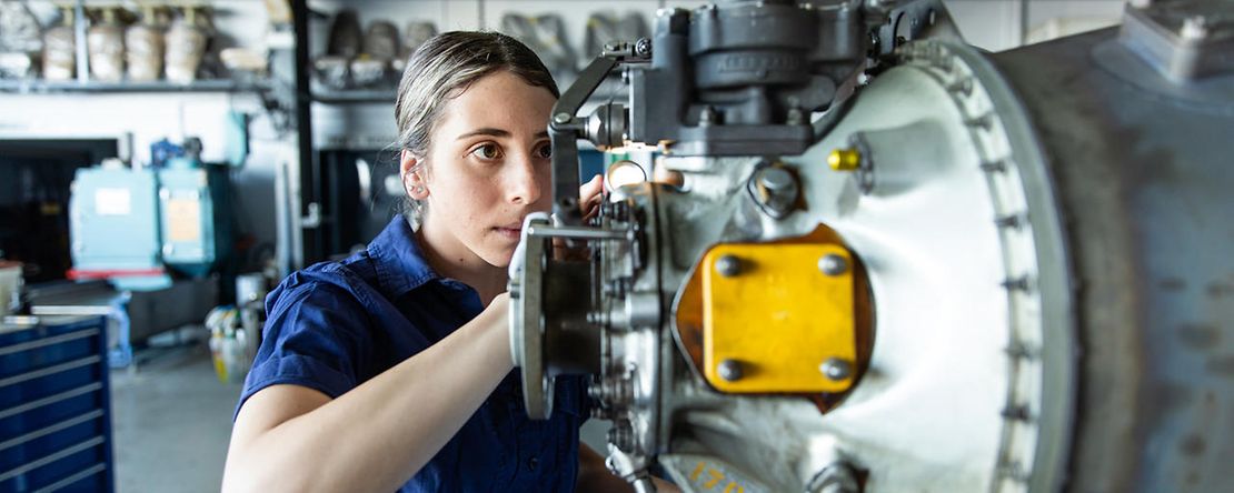 Junge Frau arbeitet an einer Maschine und bedient diese