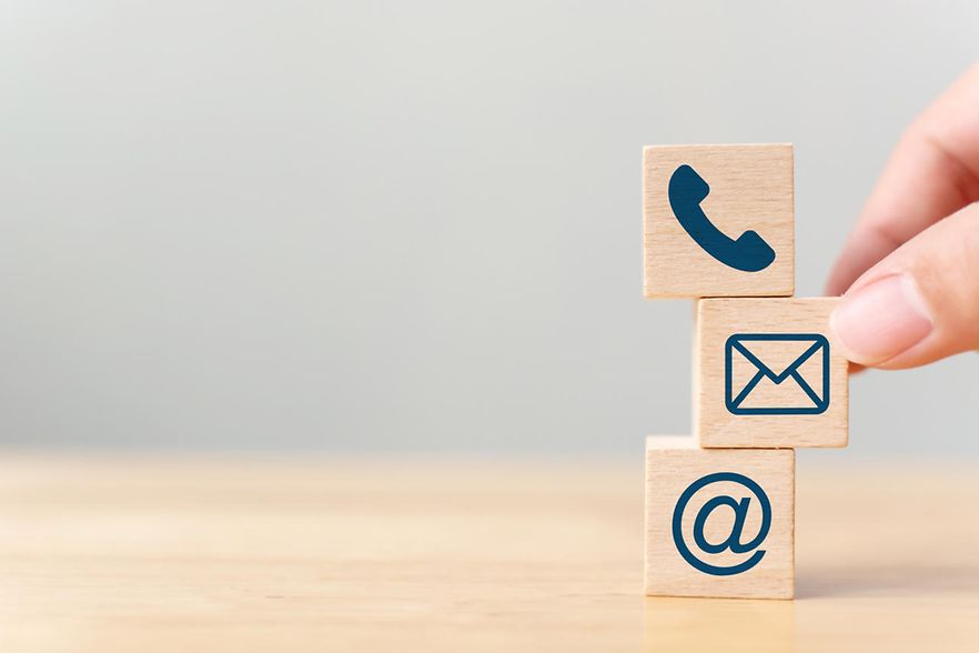 Hand greift nach Holzbl&ouml;cken mit Icons f&uuml;r E-Mail und Telefon