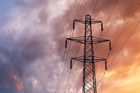 Detail of a British Style Electricity Pylon and suspended electic cables against a Blue Cloudy Sky