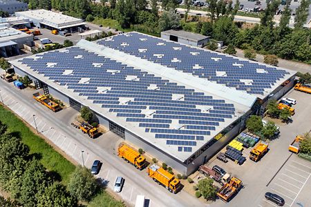 Large industrial building, solar panels and trucks - aerial view