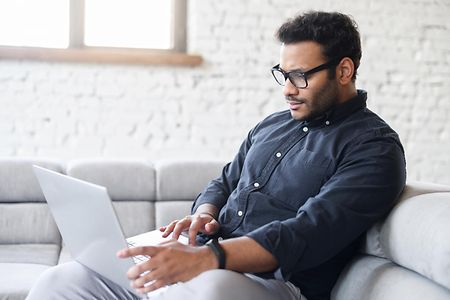 Serious multiracial man using laptop computer for remote work from home