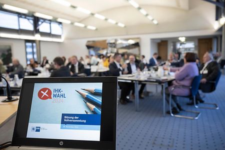 Bildschirm mit P&auml;sentation, im Hintergrund Gespr&auml;che an Tischen