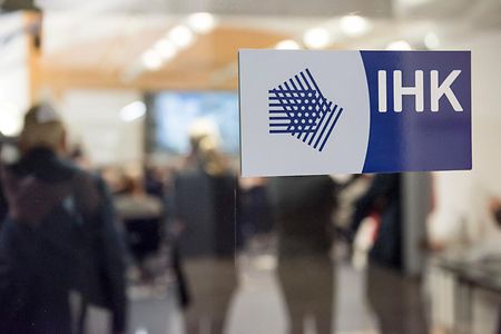 Glast&uuml;r mit Logo, im Hintergrund Menschen