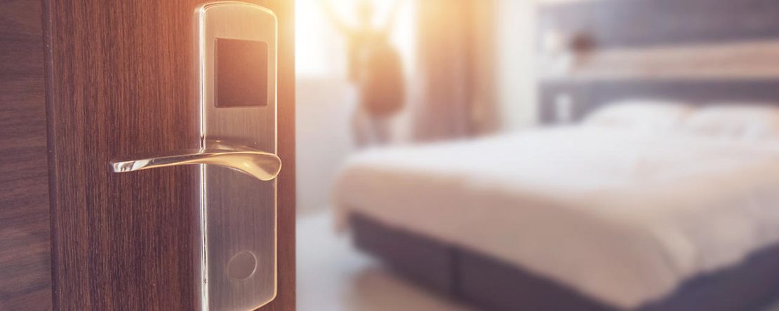 Der Blick geht durch eine offene T&uuml;r in ein sonnendurchflutetes Hotelzimmer.
