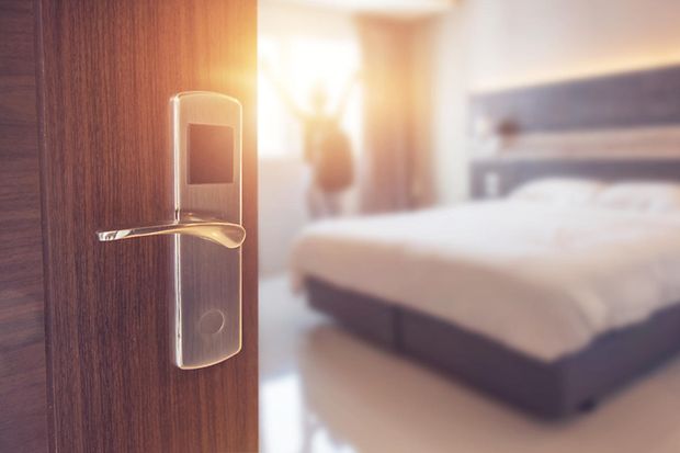 Der Blick geht durch eine offene T&uuml;r in ein sonnendurchflutetes Hotelzimmer.