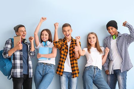 Portr&auml;t von gl&uuml;cklichen jungen Sch&uuml;lern vor buntem Hintergrund