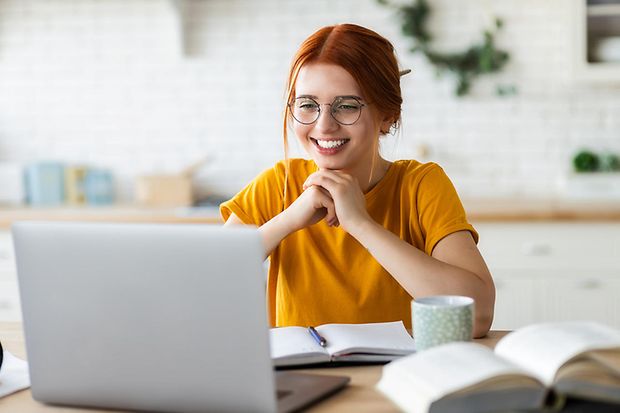 Eine junge rothaarige Frau lernt in einer Arbeitsgruppe am PC