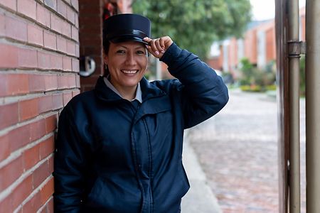 Security guard opening the door of a gated community and greeting with her hat