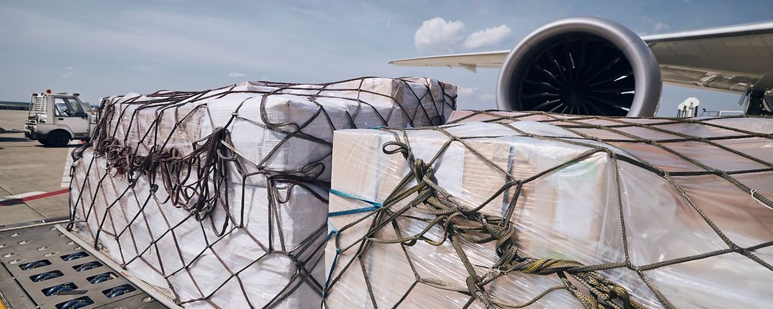 Frachtcontainer vor dem Triebwerk eines Frachtflugzeugs.