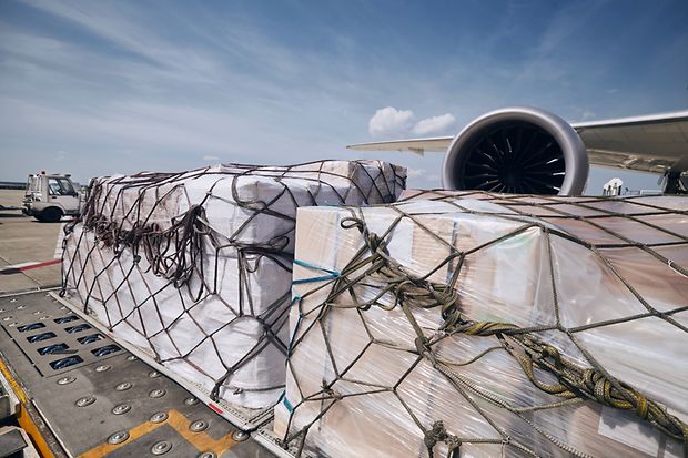 Frachtcontainer vor dem Triebwerk eines Frachtflugzeugs.