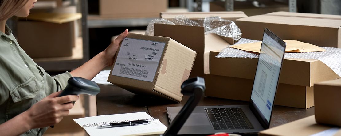 Weibliche Verk&auml;uferin scannt E-Commerce-Versandbox