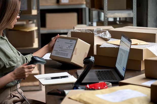 Weibliche Verk&auml;uferin scannt E-Commerce-Versandbox