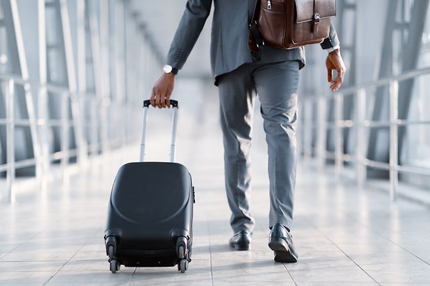 Symbolbild: Businessmann am Flughafen zieht Reisekoffer hinter sich her