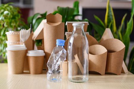 Plastic and glass bottle on the background of eco-friendly paper tableware. The concept of using biodegradable materials.