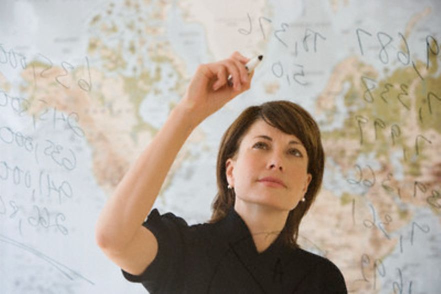 Eine Frau vor einer Weltkarte beschreibt ein transparentes Whiteboard