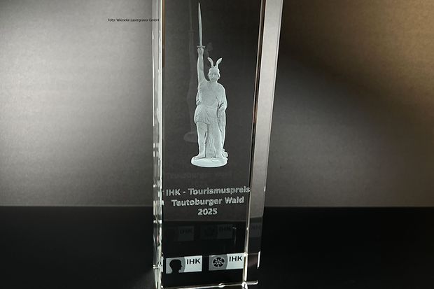 Gl&auml;serne Troph&auml;e mit Hermannsdenkmal und Aufschrift &bdquo;IHK-Tourismuspreis Teutoburger Wald 2025&ldquo;