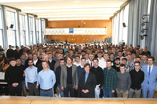 Absolvierende der Ausbildungswinterpr&uuml;fungen aus Bielefeld und G&uuml;tersloh stehen vor der B&uuml;hne in der Aula.