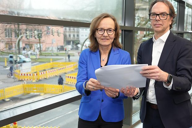Zwei Akteuere der IHK halten die Ergebnisse der Studie "Vitale Innenst&auml;dte" f&uuml;r Bielefeld in die Kamera.