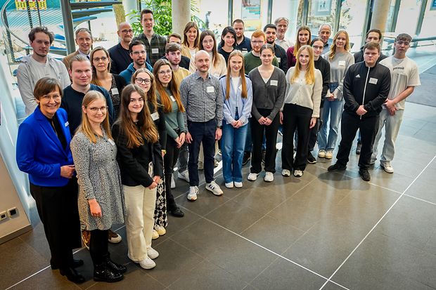 Die geehrten DIGIZUBIS, ihre Ausbilder und die IHK-Coaches stehen im Foyer und blicken in die Kamera.