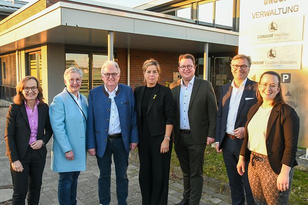 Die Gruppe steht vor dem Verwaltungsgeb&auml;ude der Condor Group und blickt in die Kamera.