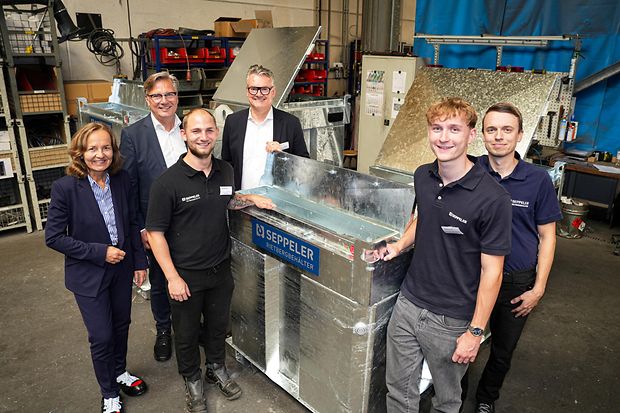 Gruppe von sechs Personen in Werkhalle um Seppeler-Metallbeh&auml;lter versammelt