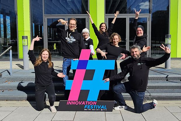Das Organisationsteam posiert vor dem Logo des Innovation Festivals
