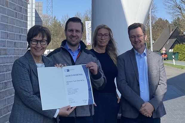 Die Beteiligten stehen vor der Firma W&ouml;rmann Team GmbH und halten die Urkunde "IHK-anerkannter Ausbildungsbetrieb" in die Kamera