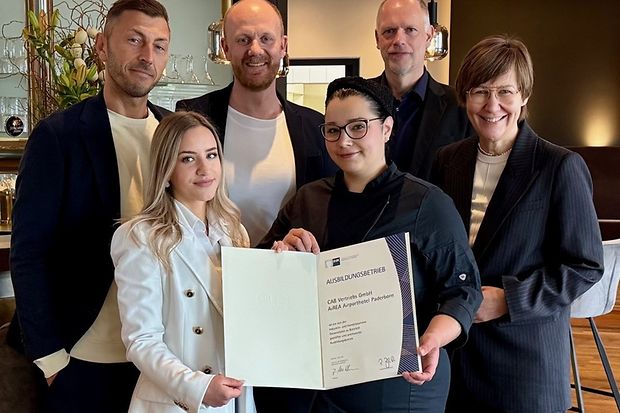 Gruppenfoto mit sechs Personen, eine Frau h&auml;lt eine Ausbildungsurkunde des AIREA Airporthotels Paderborn in der Hand.