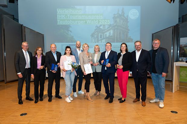 Gruppenfoto bei der Verleihung des IHK-Tourismuspreises Teutoburger Wald 2025, einige Personen halten Urkunden und Troph&auml;en