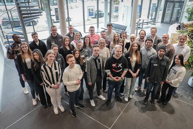 Gruppe junger Erwachsener und Betreuer steht im Foyer eines Geb&auml;udes und blickt gemeinsam in die Kamera.