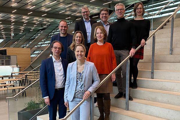 Neun Personen auf moderner Treppe in hellem Geb&auml;ude &ndash; Gruppenfoto.