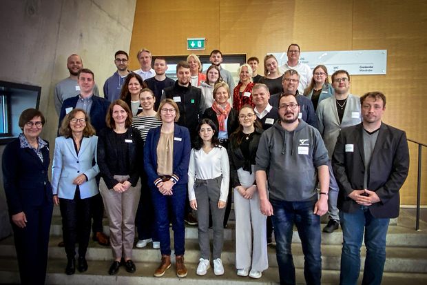 Gro&szlig;e Gruppe aus verschiedenen Altersgruppen posiert auf einer Treppe bei einer IHK-Veranstaltung