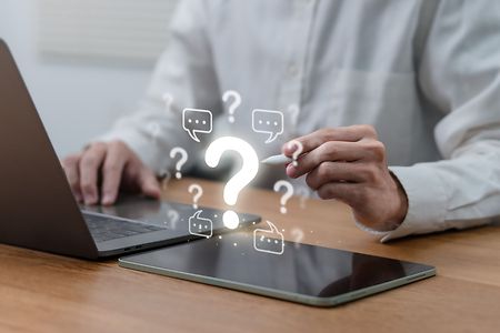 Person am Laptop mit schwebenden Fragezeichen &ndash; Symbol f&uuml;r digitale Beratung.