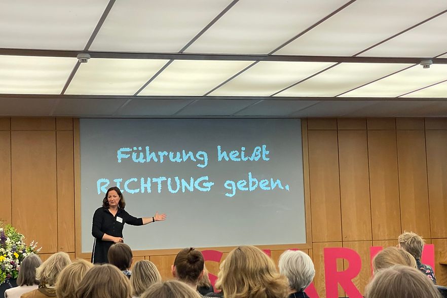 Vortragsszene mit dem eingeblendeten Satz &bdquo;F&uuml;hrung hei&szlig;t Richtung geben&ldquo;