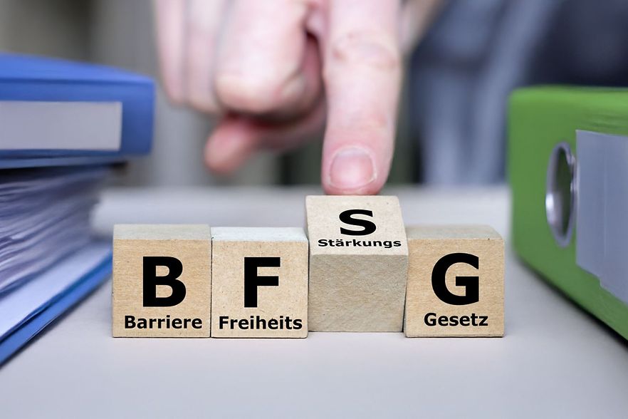 Hand bewegt Holzbausteine mit Aufschrift Barrierefreiheitsst&auml;rkungsgesetz