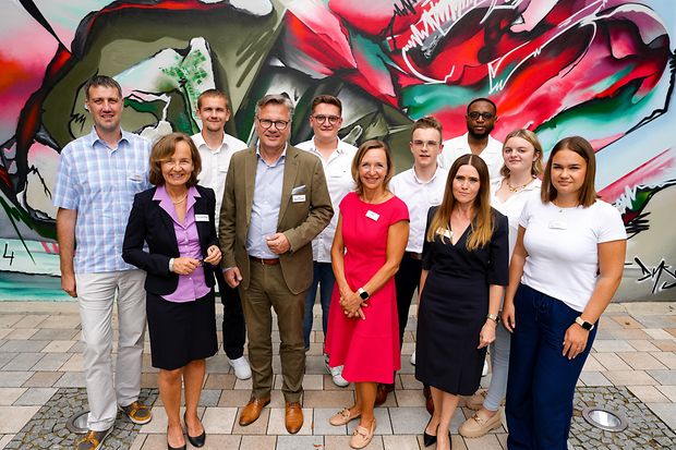 Team vor Graffiti-Wand: Gruppenbild junger Menschen und IHK-Vertreter:innen vor bunter Wand mit Graffiti.