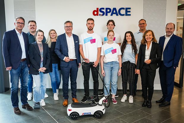 Unternehmensbesuch bei dSPACE mit jungen Mitarbeitenden und Mini-Elektrofahrzeug.