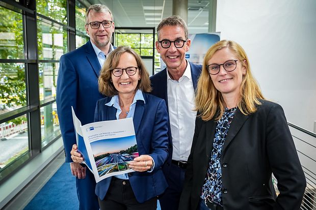 Vier Personen posieren mit einer Brosch&uuml;re &uuml;ber Infrastruktur und Mobilit&auml;t.