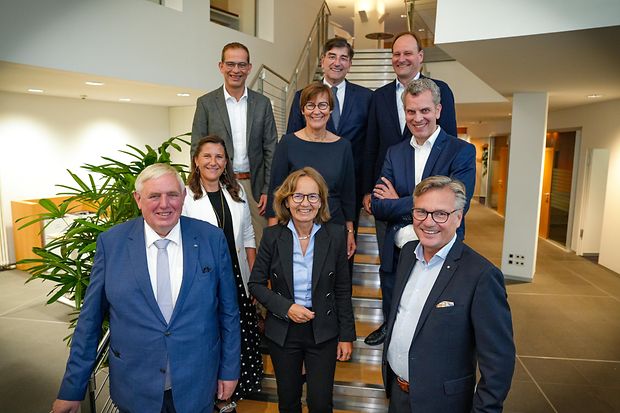Eine Gruppe von Gesch&auml;ftsleuten steht auf einer Treppe und l&auml;chelt in die Kamera.